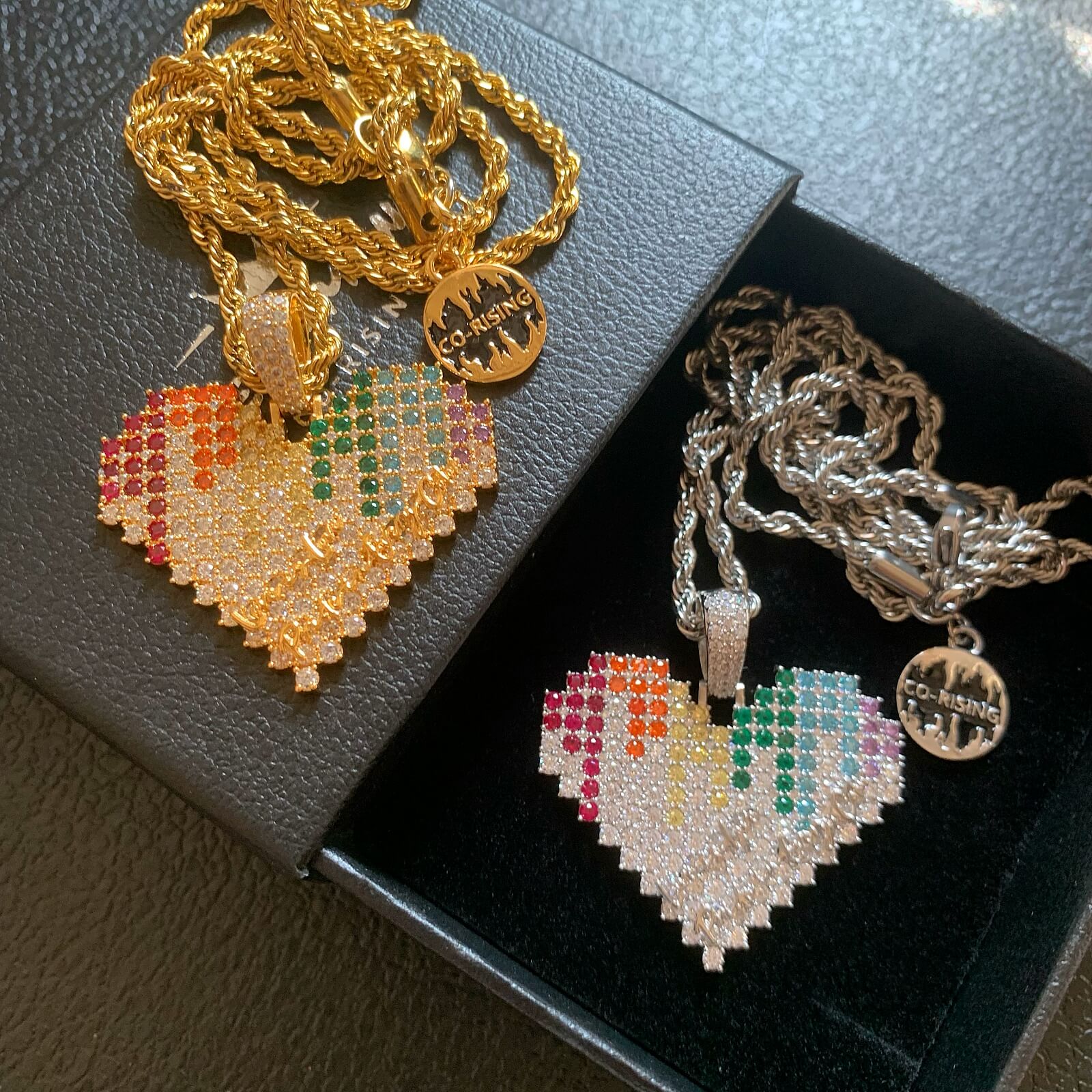 Gold and white gold ICEDIAMOND spectrum heart pendant necklaces displayed together
